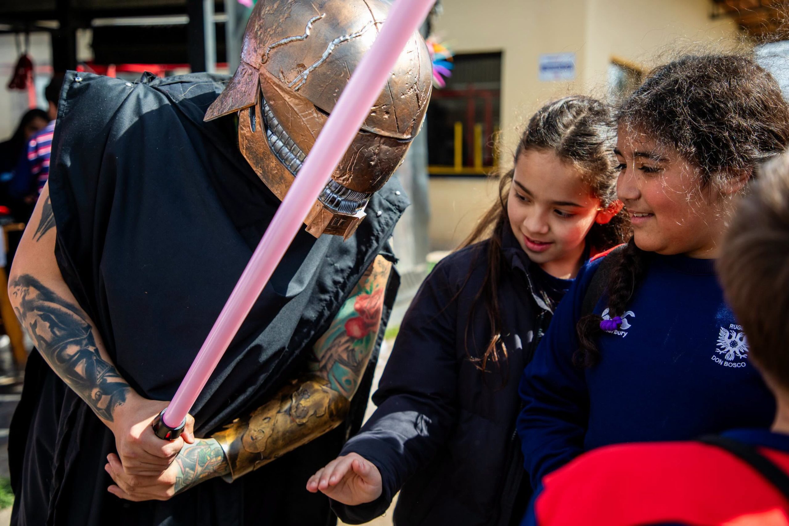 Dos nenas de Don Bosco conociendo el sable de luz de un personaje durante el evento de Star Wars en Bernal
